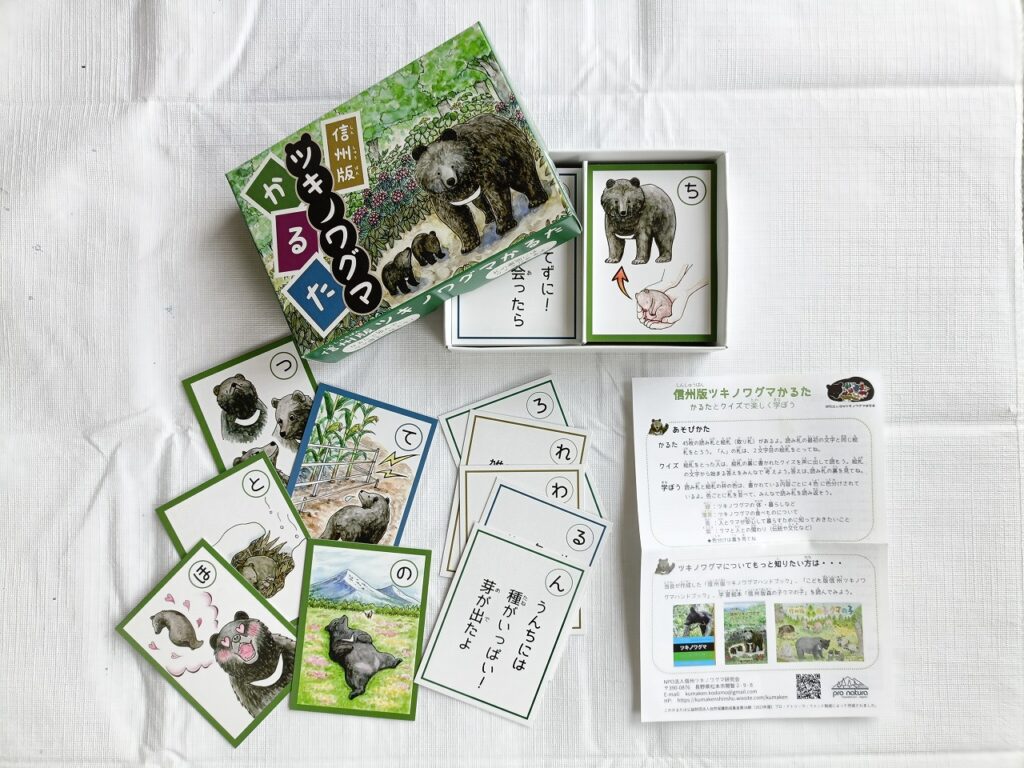信州版ツキノワグマかるたの内容。遊び方の説明書、ツキノワグマに関する読み札、水彩絵具で色付けされた様々なクマのイラストが描かれた絵札が入っている。